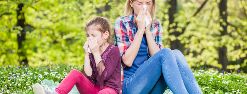 An image of mother and daughter with seasonal allergies blowing their noses.