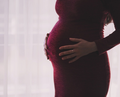 An image of the torso of a pregnant woman wearing a dress.